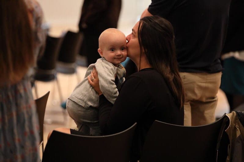 En mor kysser sin baby på kinden under gudstjenesten