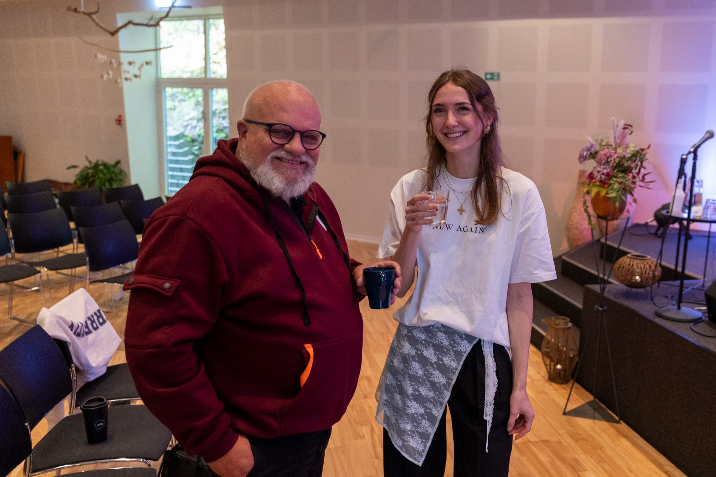 To fra kirken smiler imødekommende med kaffe i hånden i kirkesalen